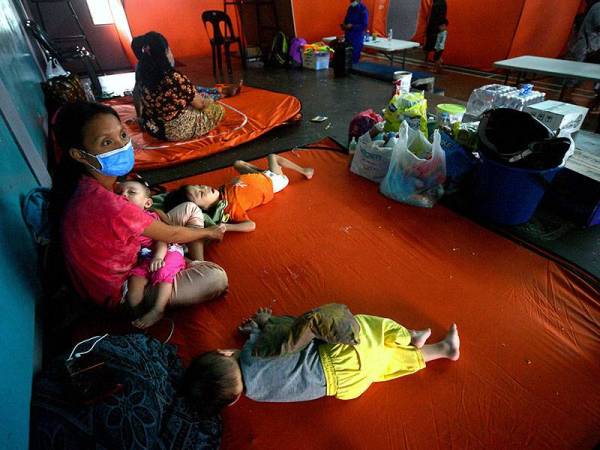 Mangsa banjir, Kasnawati Ram, 29, (kiri) bersama anak-anaknya ditempatkan di PPS Dewan Taman Malihah, Kuching pada Khamis.