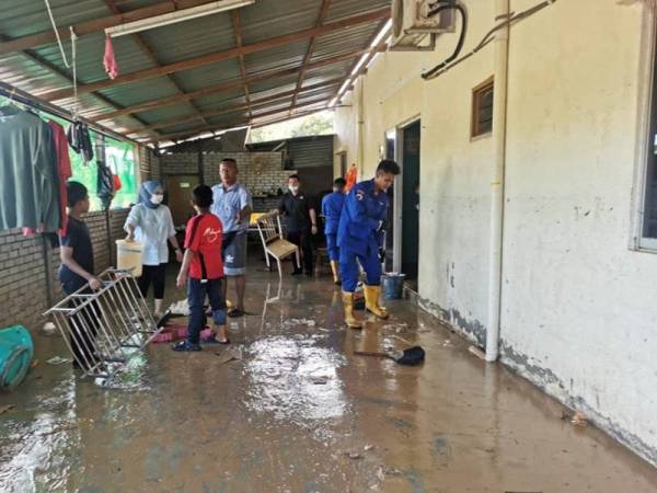 Anggota Angkatan Pertahanan Awam membantu mangsa banjir membersihkan kediaman mereka di Kampung Seremin, Segamat.