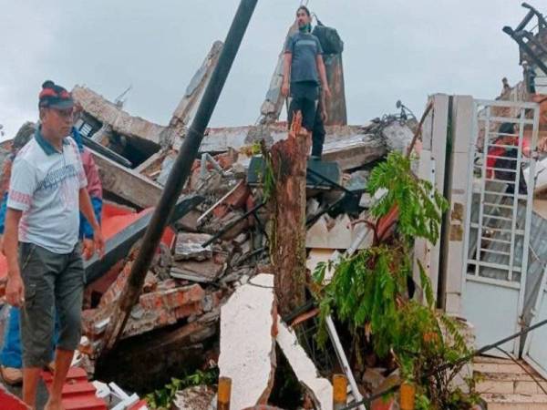 Seorang penduduk memeriksa runtuhan rumahnya akibat gempa bumi di Mamuju, Sulawesi Barat pada Jumaat. - Foto CNN