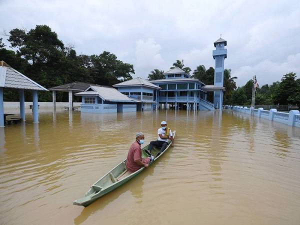 Penduduk Kampung Aceh, Pekan, Mohd Rashik Ujang, 57, dan Mohamad Naziri Razali, 48, mendayung sampan ketika meninggalkan pekarangan masjid selepas menunaikan solat Jumaat ketika tinjauan hari ini.  - Foto Bernama