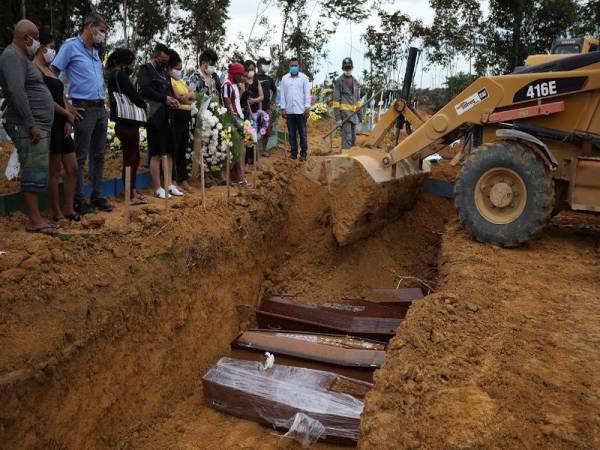 Sebuah jentolak digunakan pada majlis pengebumian beramai-ramai pesakit Covid-19 di tapak perkuburan Parque Taruma di Manaus, Brazil. - Agensi