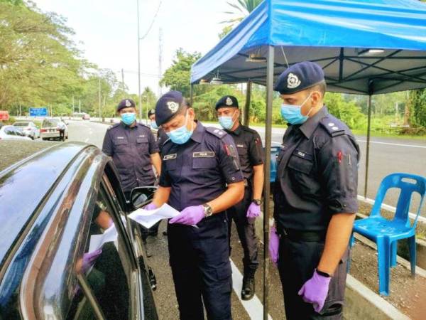 Sulizmie Affendy memeriksa surat kebenaran rentas negeri pada sekatan jalan raya Taman Universiti, Tanjung Malim. Foto: Ihsan pembaca