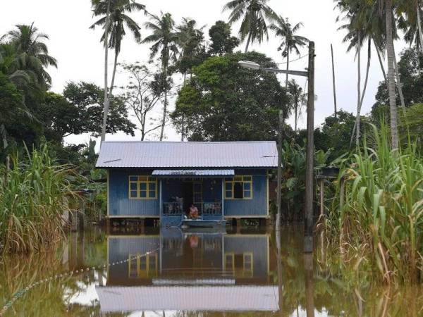 Penduduk Kampung Tanjung Medang, Pekan Pahang, Nor Azah Awang, 44, bersama suami Shahrun Mohd Yunos, 62, termenung di beranda rumah melihat banjir yang masih mengelilingi rumah mereka.