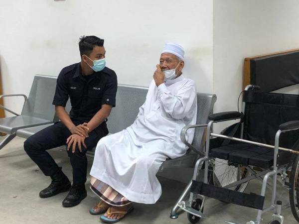 Tertuduh, Lokman Ahmad, 83, (kanan) dikawal polis keluar dari Mahkamah Majistret selepas denda diputuskan terhadapnya atas dua kesalahan yang dilakukan.