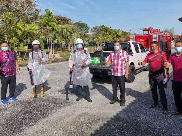 Kok Yew (tiga, kanan) bersama sebahagian anggota bomba sukarela yang melakukan proses nyah cemar di sekolah.