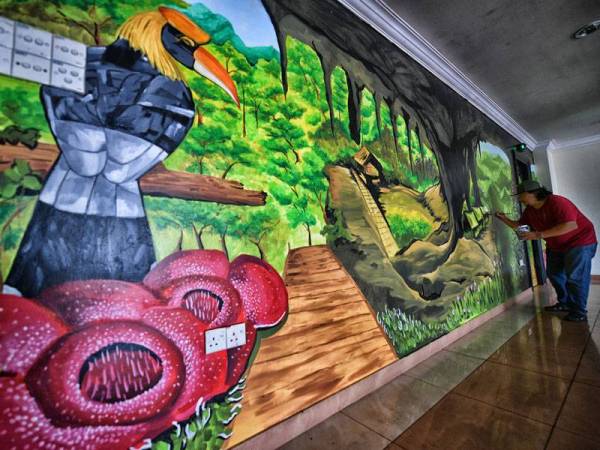 Pelukis mural, Kassmadi Morshidi, 42, menyiapkan lukisan mural di bangunan RTM Sarawak di Kuching iaitu projek terbaharu mereka.- Foto Bernama