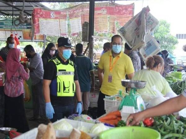 Kelihatan anggota polis melakukan pemeriksaan pematuhan SOP di Pasar Awam Nilai.