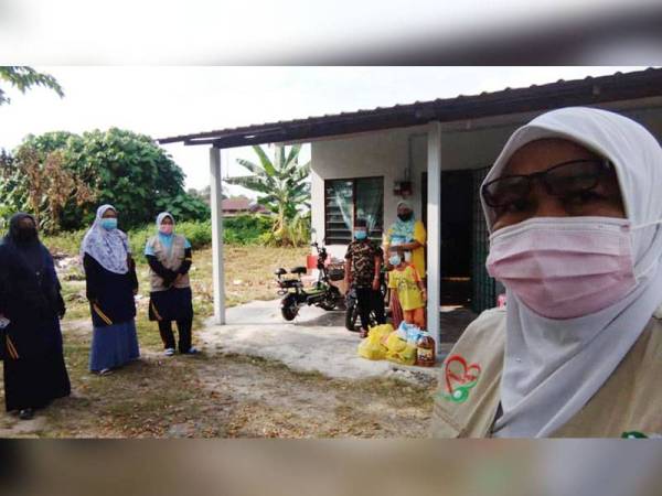 Jatimah bersama dua cucunya ketika menerima bantuan makanan asas di rumahnya di Kampung Tengah Batu 13, Puchong. - Foto FACEBOOK LZS