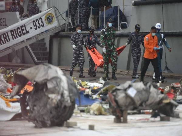 Anggota pasukan penyelamat Indonesia membawa serpihan pesawat Sriwijaya Air SJ-182 di Pelabuhan Tanjung Priok di Jakarta, Indonesia. Foto Xinhua