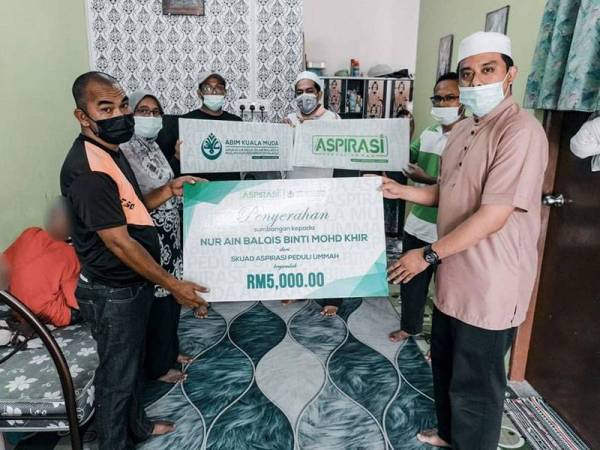 Amir menyampaikan sumbangan kepada Mohd Khir (kiri) sebanyak RM5,000 bagi meringankan beban keluarga itu.