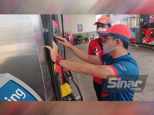 Cheng Seng sedang mengajar Lester Mohd menggunakan sistem pam minyak di Stesen Minyak Caltex Bachang, di sini, pada Sabtu.