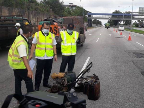 Solihan (tengah) diberi penerangan mengenai kerja-kerja menaik taraf dan menampal lubang Lebuhraya Pasir Gudang di Pasir Gudang, pada Ahad.