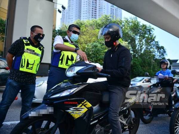 Ketua Polis Daerah Petaling Jaya, Asisten Komisioner Nik Ezanee Mohd Faisal (dua dari kiri) memeriksa dokumen yang diberikan penunggang motosikal di sekatan jalan raya di Persiaran Surian, Petaling Jaya dalam Program Warn and Sweep pada Ahad. Foto - ASRIL ASWANDI SHUKOR