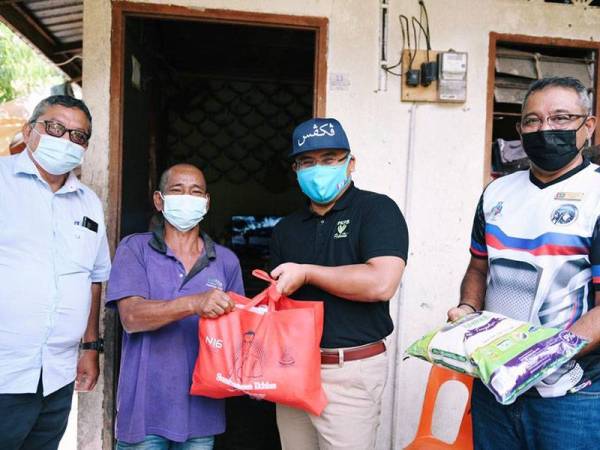 Amirudin (dua dari kanan) menyerahkan bakul makanan kepada seorang penduduk di kawasan Orang Asli di Ulu Batu Gombak.