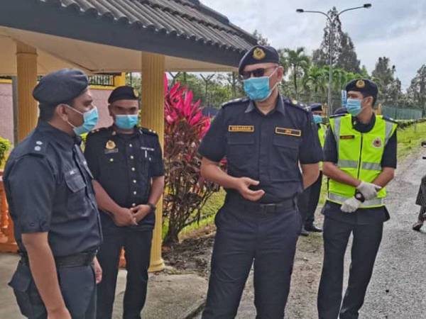 Zulkarnain (tengah) berbincang sesuatu dengan anggota PDRM semasa turun padang menghantar bekalan makanan kepada anggota SJR di Stesen Penguatkuasaan Air Sejuk, Kemaman pada Rabu.