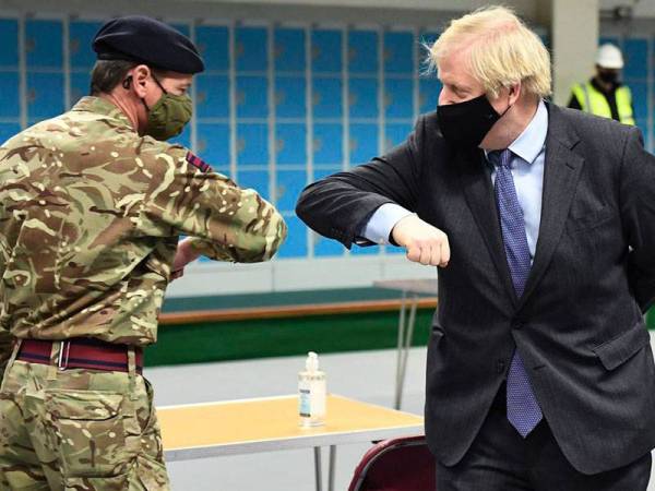 Johnson (kanan) bersalam siku ketika bertemu dengan anggota tentera yang bertugas di pusat vaksinasi di daerah Castlemilk di Glasgow pada Khamis. - Foto Agensi