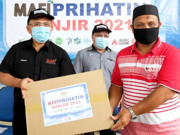 Ronald (kiri) serahkan bantuan keperluan makanan pada majlis di Pejabat PPK Beluran pada Sabtu. - Foto Ihsan MAFI