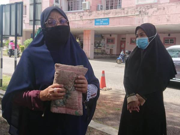 Norlida (kiri) membawa bersama bantal busuk anak angkatnya yang maut disyaki didera ibu kandung ketika ditemui pemberita di Jabatan Perubatan Forensik Hospital Melaka pada Ahad.