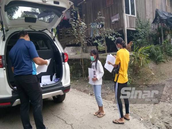 Murid orang asli beratur untuk mendapat bahan PdPR yang dihantar guru ke kampung mereka.