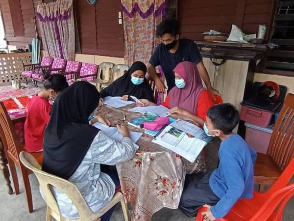 Mohamed Irfan Bahari bersama adik-adik dan sepupunya menyiapkan PdPR di rumah mereka di Kampung Serting Ilir, Jempol.