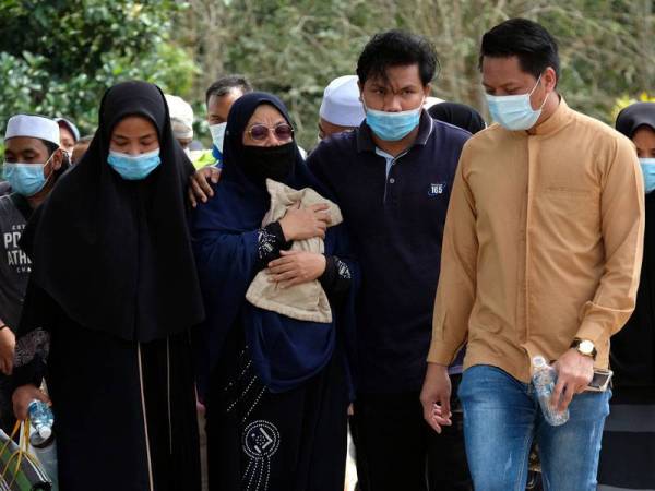 Ibu angkat kepada kanak-kanak lelaki berusia tujuh tahun yang maut, Norlida Abu Hassan, 50, (depan, tiga kanan) memeluk erat bantal busuk milik kanak-kanak itu ketika hadir pada majlis pengkebumian di Tanah Perkuburan Islam Padang Lebar dekat Simpang Bekoh, hari ini. - Foto Bernama