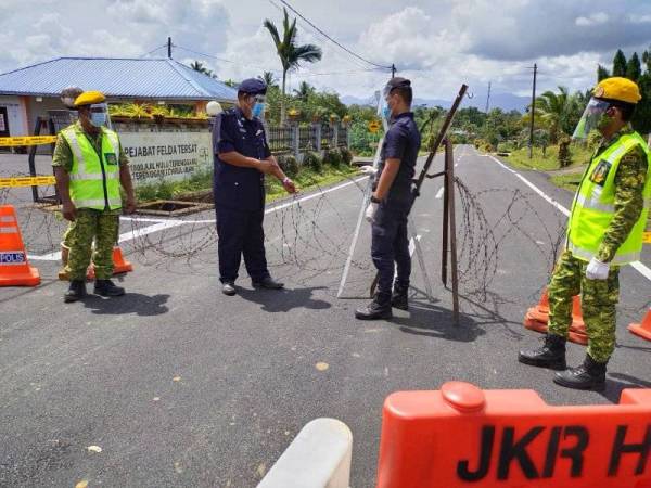 Mohd Adli (dua kiri ) memeriksa kawat duri yang dipasang di laluan utama keluar masuk ke Felda Tersat, Ajil, Hulu Terengganu, sempena pelaksanaan PKPD, Khamis