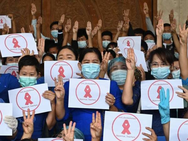 Kumpulan pengajar menunjukkan simbol hormat tiga jari dan reben merah ketika membantah rampasan kuasa di Dagon University di Yangon pada Jumaat. - Foto: AFP