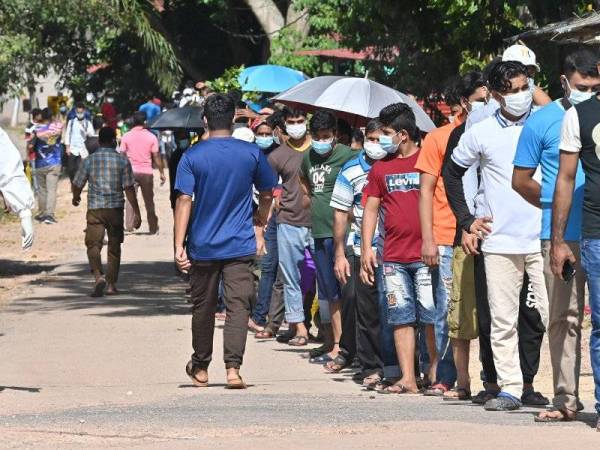 Sebahagian pekerja asing di sebuah kilang memproses ayam di Serkam,Jasin beratur panjang untuk menjalani ujian saringan Covid-19 pada Sabtu.