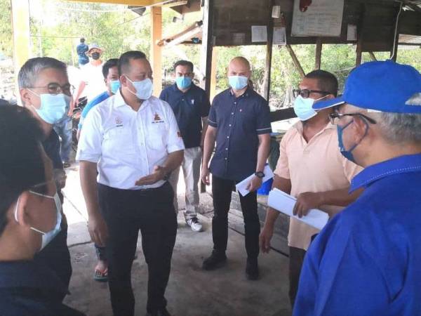 Tengku Zafrul (dua dari kiri) mendengar penerangan Mohd Fadli (dua dari kanan) pada lawatannya ke Jeti Nelayan Kampung Simpang Empat BNO pada Ahad.