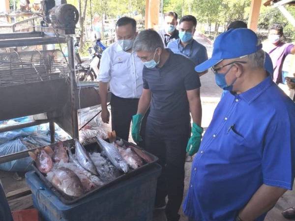 Tengku Zafrul (tengah) diiringi Pengerusi UMNO Selangor, Tan Sri Noh Omar (kanan) dan Rizam (kiri) pada lawatannya ke Jeti Nelayan Kampung Empat Simpang Bagan Nakhoda Omar, Sabak Bernam pada Ahad.