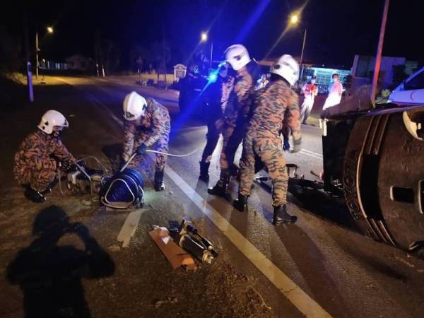 Anggota bomba mengeluarkan mangsa yang tersepit selepas forklift yang dibawanya terbalik dan menghempapnya di Jalan Hasyim, Kampung Parit Hasyim, Ayer Hitam, Batu Pahat pada Isnin.