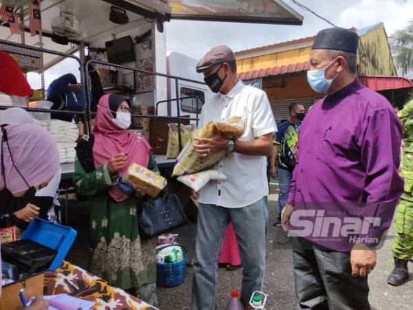 Rosol (dua dari kanan) berkata sesuatu kepada pelanggan Prihatin Mart yang membeli barangan keperluan di kedai runcit bergerak itu.