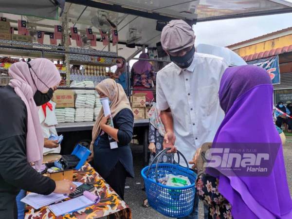 Rosol (dua dari kanan) bertanya khabar seorang warga emas yang datang memberi barang keperluan di Prihatin Mart.