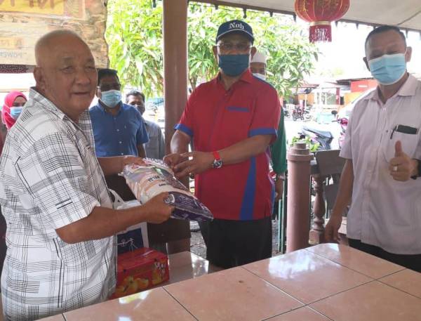 Noh (tengah) menyampaikan sumbangan barangan keperluan kepada penerima pada majlis di Kampung Tiram Jaya, Tanjong Karang pada Selasa.