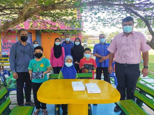 Syed Mohd Johan Rizal (kanan) bersama anak-anak Nor Shamsina dan Abd Majid selepas menyerahkan dua tablet kepada keluarga berkenaan di SK Mergong di sini pada Selasa.