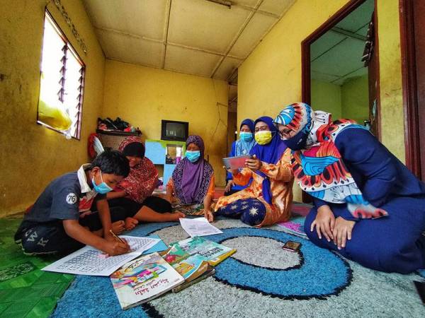 Azilawati (kanan) bersama dua guru SK Dato' Wan Kemara sempat melihat anak murid mereka melakukan tugasan yang diberikan ketika sesi menghantar bahan pengajaran di rumah.