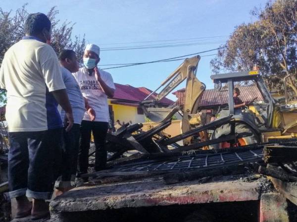 Usahawan yang juga sukarelawan Ebit Lew (kanan) bersama Mohd Yazid (tengah) melihat tapak rumah terbakar di Kampung Pengkalan Nangka Pengkalan Chepa pada Rabu. FOTO: BERNAMA