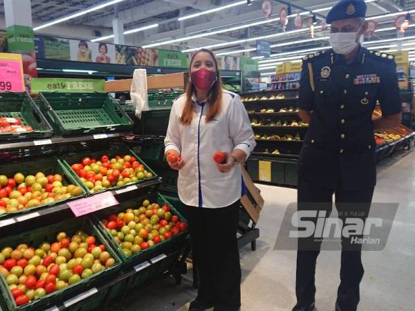 Norena (kiri) menunjukkan tomato antara sayur-sayuran yang termasuk dalam skim kawalan harga sempena perlaksanaan Skim Harga Maksimum Musim Perayaan (SHMMP) Tahun Baru Cina 2021 di pasaraya Tesco Bandaraya Melaka di sini, pada Khamis.