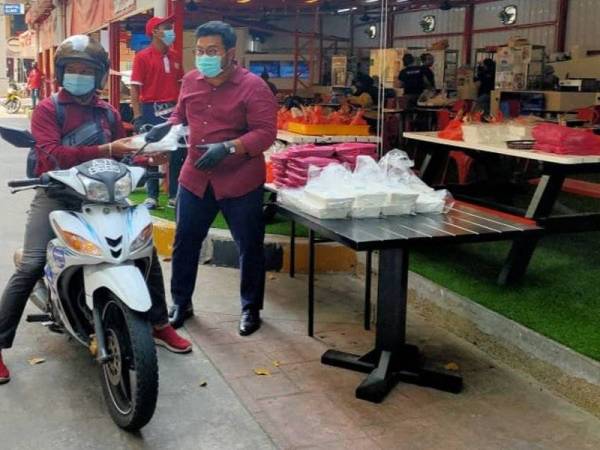 Megat D Shahriman menyampaikan pek makanan percuma kepada salah seorang penghantar makanan di Don's Food Corner di Plaza Damas, Kuala Lumpur pada Rabu.