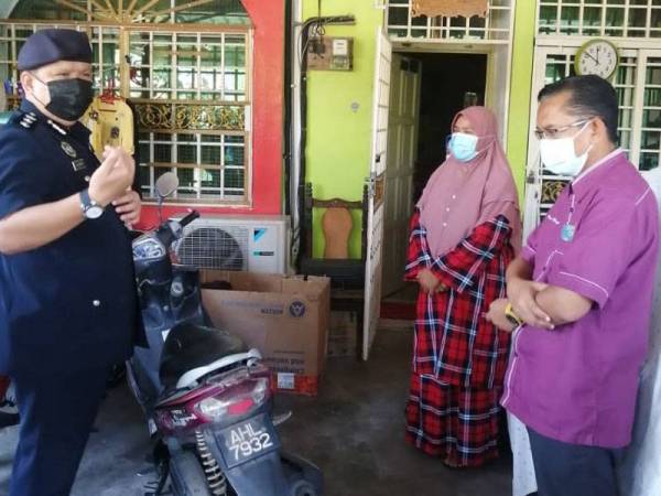 A Asmadi (kiri) bersama Meor Hezbullah ketika menyantuni ahli keluarga mangsa di Klebang Restu, Chemor pada Rabu.