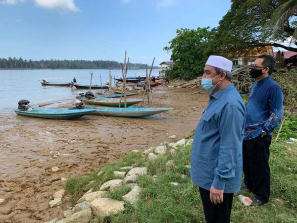 Izani (dua dari kanan) melihat tempat bot penambang diletakkan di tepi sungai Kelantan, Kuala Besar di sini.