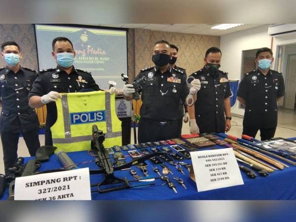 Osman (tengah) memegang pistol dan gari yang dirampas daripada geng Ah Fatt ketika sidang akhbar di Taiping pada Khamis.