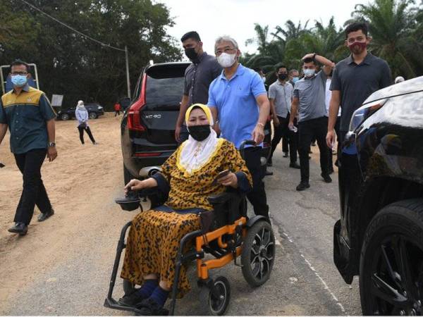 Al-Sultan Abdullah berkenan menolak kerusi roda seorang penduduk orang kurang upaya, Robiani Bakar, 58, ketika berangkat melihat proses pembinaan rumah baharu kepada mangsa banjir di Kampung Tanjung Pulai hari ini. - Foto Bernama