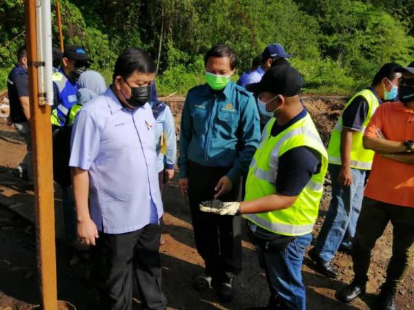 Loy Sian (kiri) mendengar penerangan berhubung insiden pencemaran berpunca daripada operasi premis kilang pengasingan logam tersebut.