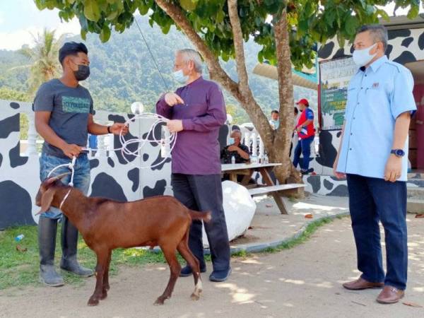 Dari kanan: Nik Roslan dan Kamarudin menyampaikan bantuan baka kambing dari Kada kepada Nik Syazwan Najmi Sukeri, 21, di Jeram Mengaji, Pasir Puteh pada Ahad.