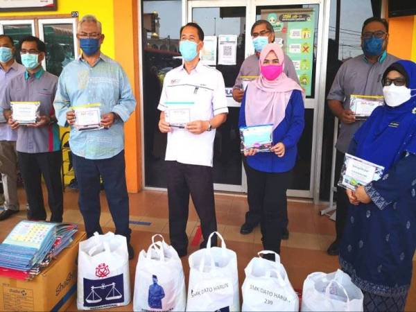 Noh (dua dari kiri) bergambar pada majlis penyampaian alat tulis kepada calon SPM di SMk Dato' Harun pada Rabu.