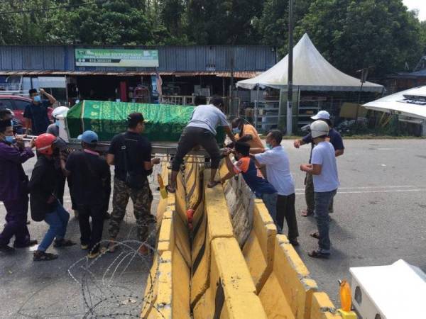 Gambar beberapa orang mengusung sebuah keranda melepasi batu penghadang jalan yang didirikan di kilometer 20, Jalan Rawang – Sungai Choh di sini tular sekali lagi.