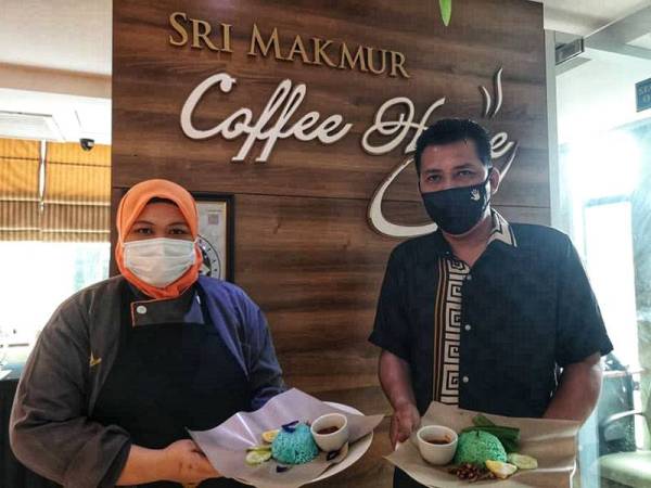 Mansor (kanan) bersama kakitangannya menunjukkan nasi lemak pandan dan bunga telang yang dijual secara pandu lalu.