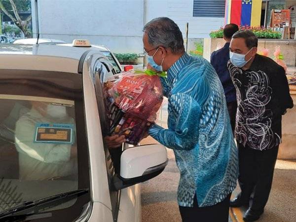 Mahadi (kemeja batik biru) menyerahkan bantuan kepada 300 pejuang veteran secara pandu lalu di pekarangan Menara DBKL 1, Jalan Raja Laut, pada Khamis.