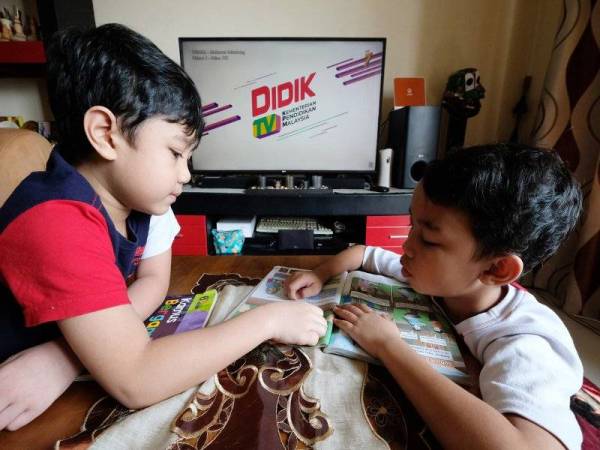 Muhammad Afif Darwish Mohd Rashdan, 7, (kiri) bersama abangnya Muhammad Alif Daniel Mohd Rashdan, 9, (kanan) menonton program DidikTV@NTV7 di kediamannya pada Rabu.